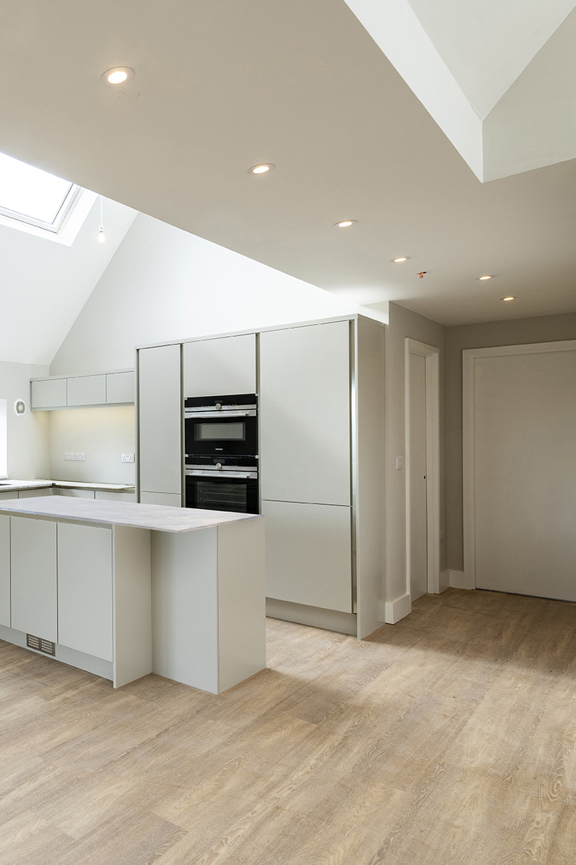 The kitchen of one of the flats are finished with a white countertop and white cabinets which help to brighten enlarge the space.