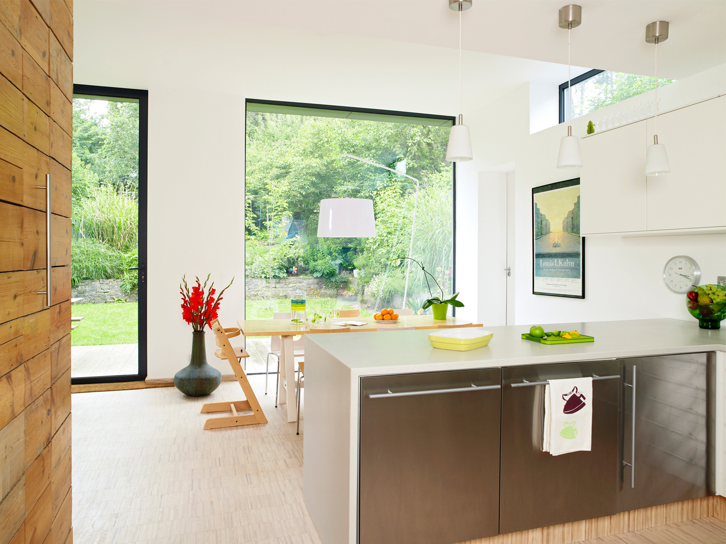 a view of a kitchen and dining area with huge 3 meter tall windows looking out into the garden